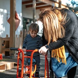 Woman helping little boy with trike